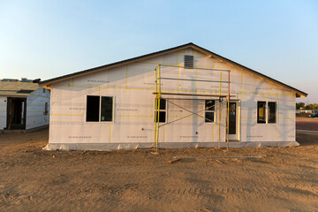 Fototapeta na wymiar House covered in construction mesh and foam panels scaffolding setup ready to install other parts