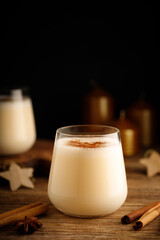 Festive eggnog cocktail in a glass on a black background