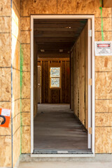 Open door and stick built unfinished construction hallway down the center of a structure