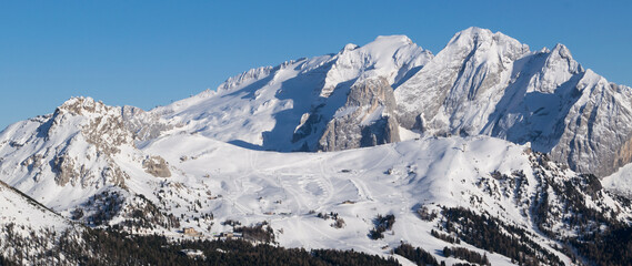 Panorama sul Ghiacciaio della Marmolada in inverno, paesaggio innevato verso le vette e le piste da sci di Canazei in Trentino - obrazy, fototapety, plakaty