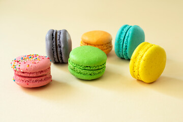 Sweet and colorful macarons on a yellow background, side view.