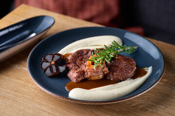 Osso buco, cooked Veal shank. Ossobuco with puree of root vegetables and black garlic