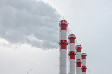 Tall smoking red and white pipes of a thermal power plant