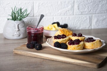 Scones with homemade blackberry jam and fresh blackberries on wooden board
