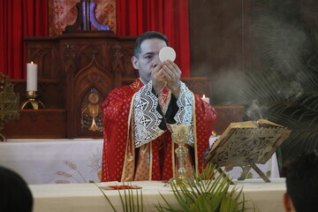 A priest celebrates a catholic mass dressed in a red chasuble 