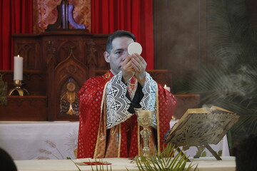 A priest celebrates a catholic mass dressed in a red chasuble 