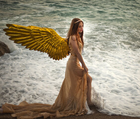 Young beautiful woman fallen angel stands on sea beach enjoy nature. costume bird white wings.