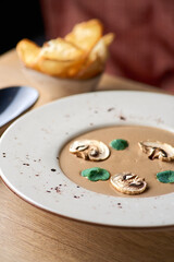 Vegetarian food. Mushroom soup puree with cream, porcini, champignons, and thymes. Copy space, wooden table