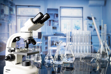 Laboratory investigations concerning test and medicine against covid. Microscope, glass tubes and beakers on blue background.