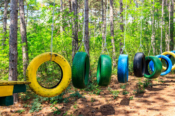 Old painted car tires suspended between trees in a rope park