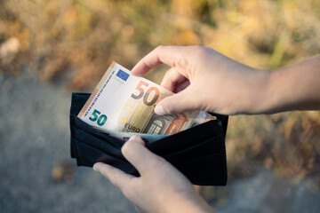 Female holding wallet with euro money. Unemployment, poverty on color background