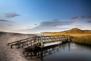 Beautiful shot of a bridge leading to a hill under the cloudy skies - Powered by Adobe