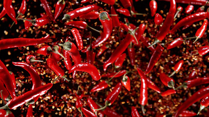 Freeze motion of flying chilli peppers on black background.