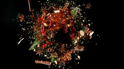 Freeze motion of flying mix of spice on black background.