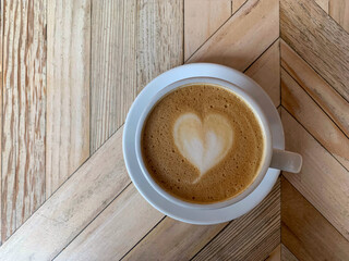Selective focus of cup of coffee latte. A mug of flat white coffee on a wooden background. Coffee art. Heart shape latte art. Horizontal.