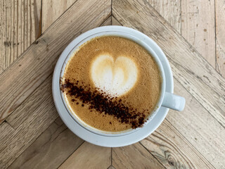 A mug of flat white coffee on a wooden background. Coffee art. Heart shape latte art Coffee in white cup