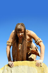 A woman is dressed as a Neanderthal warrior. 
Her body and face is covered with mud and dirt.
She...