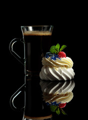 Small Pavlova dessert and mug of black coffee.