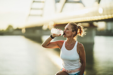 Woman Drink Water And Take A Break While Exercising Near The River