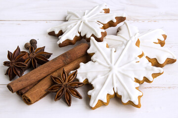 Christmas gingerbread. Edible Christmas decor concept. Gingerbread cookies in white glaze, cinnamon and spices on a light wooden background. Christmas traditions. Copy space. Flatlay. - 475905446