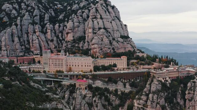 Aerial view of Santa Maria de Montserrat monastery on mountain Montserrat. Cloudy autumn weather. Slow motion