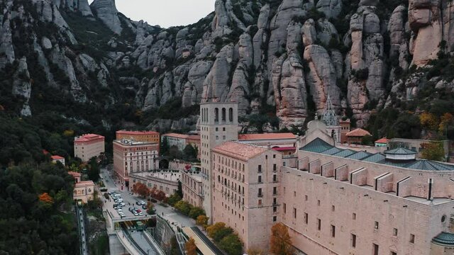 Scenic aerial view of Santa Maria de Montserrat monastery on mountain Montserrat in Barcelona, Catalonia, Spain. Walking people, parked cars