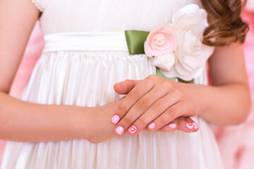 Close up view of beautiful little girl hands with gentle manicure nails, pink gel polish, hearts...