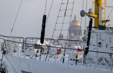 Fototapeta premium The golden dome of Isaac cathedral through old moored sail boat at frosty day, Winter landscape of St. Petersburg