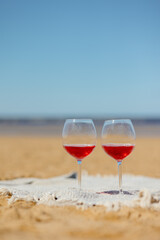 two glasses of red wine or juice at a picnic on the shore of a lake or ocean. a romantic date between two people in love. a basket with delicious food for a picnic and an outdoor dinner. beautiful