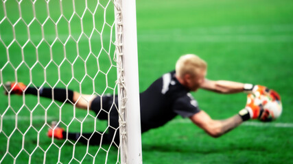 The soccer goalkeeper saves the goal from a penalty kick while jumping. Selective focus on the boom.