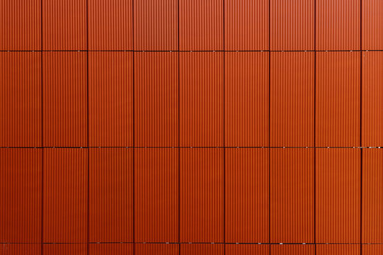 Modern facade of extruded ceramic panels. Ventilated facade made of ceramic tile in orange. Construction backgrund