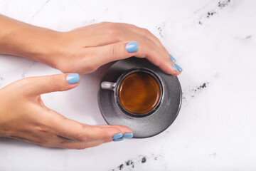 Fototapeta na wymiar Woman hands holding coffee cup of expresso blue nails