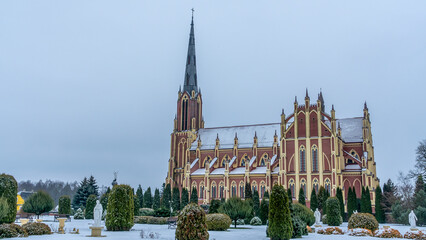 Neo-Gothic cathedral church in the town of Gervyaty in Belarus in the winter on dramatic sky background. Space for text.