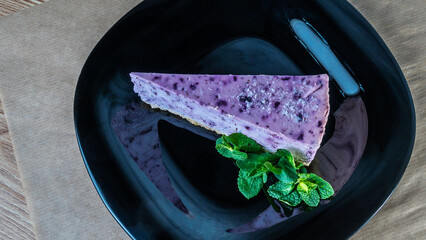 Fresh delicious piece of blueberries cake with and mint on black plate. Slice of blueberry pie with mint.