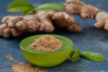 Fresh ginger root and ginger powder spice in the bowl. Healthy condiment and seasoning.