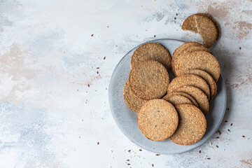 Plate with tasty crackers with sesame and flax seeds on grey stone background. Top view.