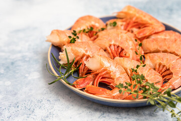 Raw red Argentine shrimps on ceramic plate, blue concrete background. Ocean jumbo shrimps.