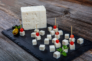 Feta Cheese Cubes on wooden cutting board. Square cubes of feta cheese isolated on wood board with...