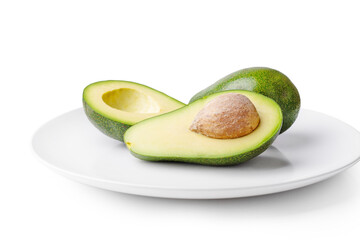 Ripe avocado and pieces of avocado in a white plate on a white background