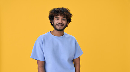 Smiling young curly indian cool positive guy standing isolated on yellow background. Happy ethnic...