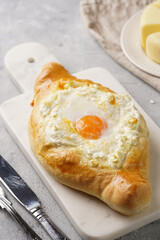 Traditional georgian dish of cheese-filled bread adjarian khachapuri with fried egg on a marble board
