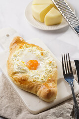 Traditional georgian dish of cheese-filled bread adjarian khachapuri with fried egg on a marble board