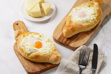 Traditional georgian dish of cheese-filled bread adjarian khachapuri with fried egg on a wooden board