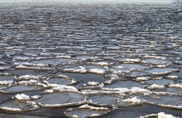 The first ice on the river at sunset. Frozen ice and snow by the river.
