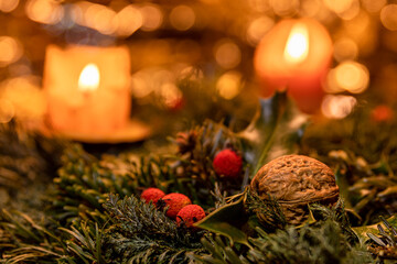 Weihnachtsschmuck mit brennenden Kerzen, Nuss und roten Beeren