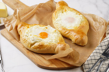 Traditional georgian dish of cheese-filled bread adjarian khachapuri with fried egg on a wooden board