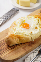 Traditional georgian dish of cheese-filled bread adjarian khachapuri with fried egg on a wooden board