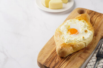Traditional georgian dish of cheese-filled bread adjarian khachapuri with fried egg on a wooden board
