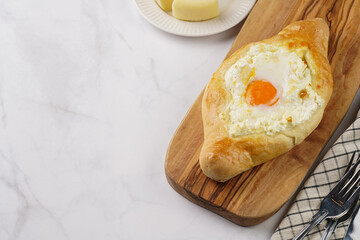 Traditional georgian dish of cheese-filled bread adjarian khachapuri with fried egg on a wooden board