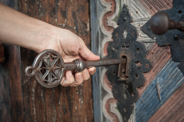 Man holds huge key in hand and unlocks large door
